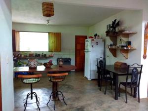 a kitchen with a table and a white refrigerator at Casa Rosa Chá em Lençóis in Lençóis +10 photos