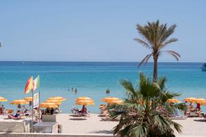 une plage avec des parasols et des gens dans l'eau dans l'établissement Appartamento Conturrana Sul Mare, à San Vito Lo Capo