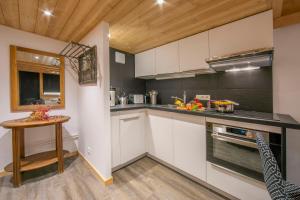cocina con armarios blancos y techo de madera en Résidence Grand Roc - Ancolies 207 - Happy Rentals en Chamonix-Mont-Blanc