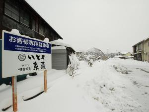 a sign in the snow next to a building at Itoya Ryokan in Nanyo