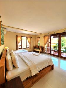 ein großes Schlafzimmer mit einem großen Bett und Fenstern in der Unterkunft BUDA AMITABA in Ubud