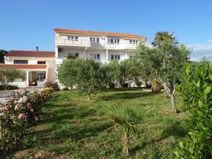 een gebouw met een tuin met bomen en struiken bij Apartments Donadic III, Caska in Novalja