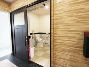 a bathroom with a toilet and a wooden wall at AMAWARI HOTEL -SEVEN Hotels and Resorts- in Uruma