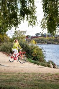 Riverfront Motel & Villas في هوبارت: امرأة تركب دراجة على مسار بجوار الماء