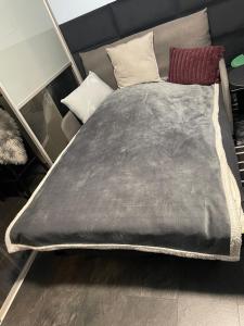 een bed met een grijze deken en 2 kussens bij Ingress in Bytom