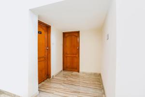 Cette chambre vide est dotée de portes en bois et de parquet. dans l'établissement FabHotel Rest & Peace, à Ahmedabad