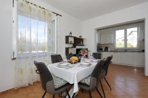 una sala da pranzo con tavolo e sedie bianchi di Holiday home Maslina a Nin