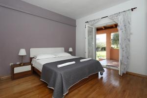 een witte slaapkamer met een bed en een glazen schuifdeur bij Holiday home Maslina in Nin