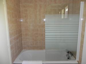 a bathroom with a shower with a white tub at Hotel Les Pins in Hourtin
