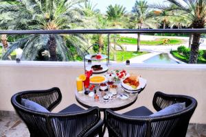 einen Tisch mit Speisen und Getränken auf einem Balkon mit Palmen in der Unterkunft Fujairah Rotana Resort & Spa - Al Aqah Beach in Al Aqah