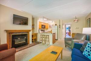 a living room with a fireplace and a kitchen at Pinnacle B04 in Killington