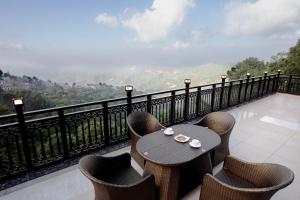 een tafel en stoelen op een balkon met uitzicht bij LUXE RESORTS - CENTRALLY HEATED AIR CONDITIONED HOTEL in THE HEART OF KASAULI in Kasauli