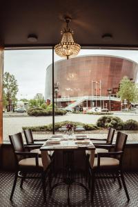 ein Tisch mit Stühlen und ein Kronleuchter vor einem Gebäude in der Unterkunft Promenade Hotel Liepaja in Liepāja + 74 Fotos