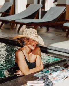 a woman in a hat sitting in a swimming pool at Der Eisvogel - Wellness- & Genusshotel in Bad Gögging