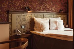 uma cama com lençóis brancos e almofadas num quarto em Promenade Hotel Liepaja em Liepāja