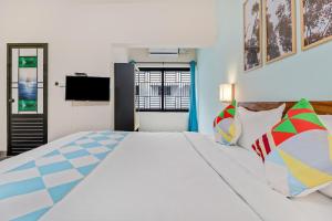 ein Schlafzimmer mit einem großen weißen Bett mit bunten Kissen in der Unterkunft OYO Home Royal Salem in Kakkayam