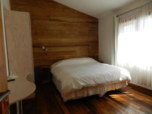 um quarto com uma cama e uma parede de madeira em Aroma Verde Hotel em Valdivia