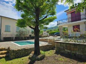 a tree in front of a house with a swimming pool at Villa Mas Fa Susa 3 étoiles avec piscine in Les Vans