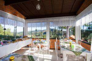 a dining room with tables and chairs and windows at Emy Pousada in Monte Verde