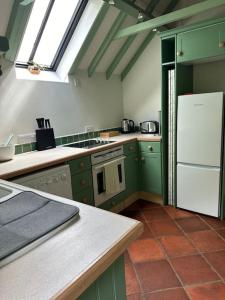 a kitchen with green cabinets and a white refrigerator at Garden Cottage in Henley on Thames
