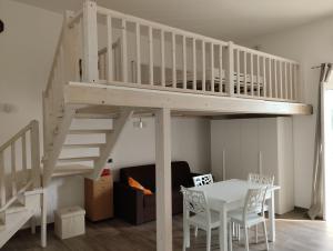 Una cama alta blanca con una mesa y un comedor. en Mirò vacanze Vieste, en Vieste