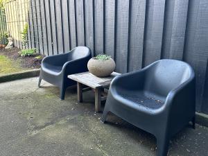 two blue chairs and a table with a vase on it at Stylish Townhouse in Havelock North