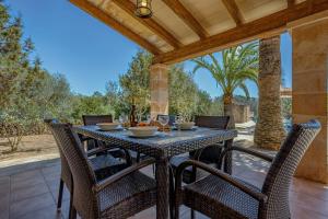 una mesa de comedor al aire libre con sillas en el patio en Rustica Talaia Vella mit Pool und Wifi, en Cala Santanyi