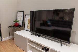 TV de pantalla plana grande en un centro de entretenimiento blanco en Friends and Family Vacation Apartments, en Riga