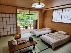 a room with two beds and a table and windows at 大和屋ホテルいろは in Nikko