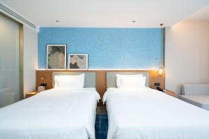 2 letti in una camera d'albergo con parete blu di Country Inn & Suite by Radisson, Wuhan Optics Valley Technology Convention and Exhibition Center a Wuhan