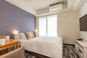a bedroom with a large white bed and a tv at Tokyu Stay Tsukiji - Tokyo Ginza Area in Tokyo