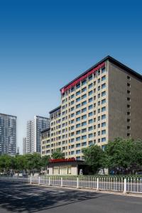 un grand bâtiment avec une clôture en face d'une rue dans l'établissement Hilton Garden Inn Beijing West Railway Station, à Pékin