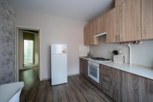 een keuken met een witte koelkast en houten kasten bij Apartments U Ratushi in Kamjanets-Podilsky