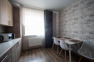 een keuken met een tafel en stoelen en een magnetron bij Apartments U Ratushi in Kamjanets-Podilsky