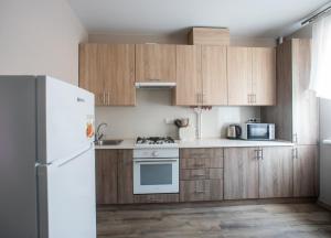 een keuken met houten kasten en een witte koelkast bij Apartments U Ratushi in Kamjanets-Podilsky