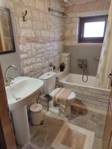 La salle de bains est pourvue d'un lavabo, de toilettes et d'une baignoire. dans l'établissement Mansion Michalis, à Rodavgi