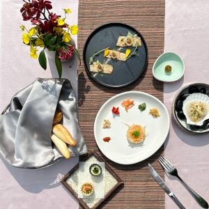 una mesa con platos de comida y un jarrón con flores en Volando Urai Spring Spa & Resort en Wulai