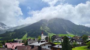 a town in front of a mountain with clouds at Almtraum Berwang in Berwang