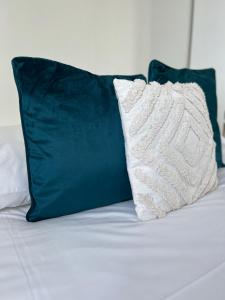 a white pillow and two green pillows on a bed at L'Isly, Dernier étage en centre de Rennes avec terrasse de 50m2 in Rennes