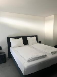 1 cama blanca grande con sábanas y almohadas blancas en Suite One Einsteinstraße, en Múnich