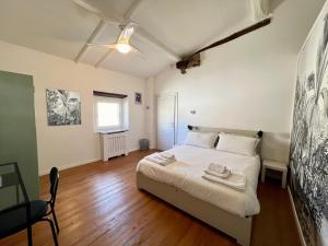 a bedroom with a bed with white sheets and wooden floors at La Matilde in Viareggio
