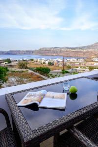 einen Tisch mit einem Buch und einem Glas Wein darauf in der Unterkunft Anya Suites Santorini in Akrotiri