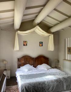 - une chambre avec un grand lit et une tête de lit en bois dans l'établissement Maison d'hôtes Campagne-Baudeloup, à LʼIsle-sur-la-Sorgue