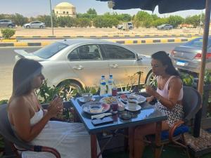 Due donne sedute a un tavolo di fronte a un'auto di Juliana Beach Hurghada a Hurghada
