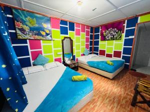 een slaapkamer met 2 bedden en een kleurrijke muur bij MUKUT CORAL CHALET in Tioman Island