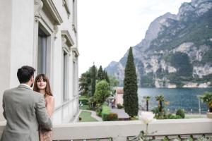 a bride and groom standing in front of a window at Lido Palace - The Leading Hotels of the World in Riva del Garda