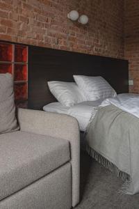 a bedroom with a bed and a couch and a brick wall at Resume apartments, Dreamer Corner No1 by Urban Rent in Kaunas