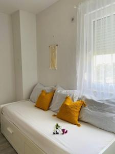 Un dormitorio con una cama con almohadas amarillas y una ventana en Apartments Ivana, en Zubovići