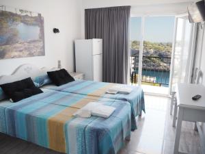 1 dormitorio con 1 cama y vistas al océano en Hotel Rocamar en Cala Figuera
