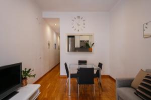 een woonkamer met een tafel en stoelen en een klok bij Cute Apartment in Barcelona